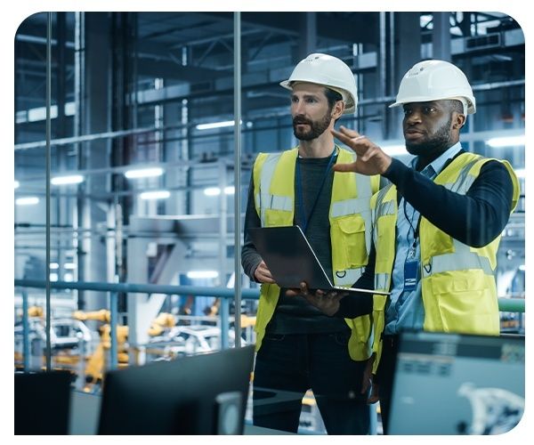 Två industriarbetare diskuterar vid produktionsutrustning